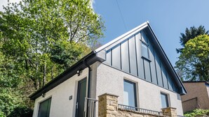A modern two-story house with a stone foundation, a sloped roof, and a large window on the upper floor. - Wayside Loft by Interhome (Drumnadrochit)