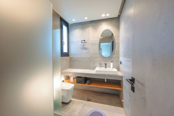Une salle de bain moderne avec un grand miroir, un lavabo et des toilettes.