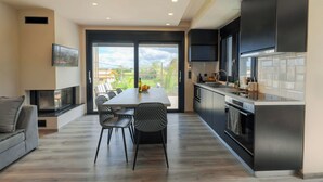 A modern kitchen with a dining area, large windows, and a fireplace. - Kourouta Luxury Suites with Pool nr3, Kourouta, Greece (Kourouta)
