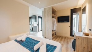 A modern hotel room with a large bed, a wooden wardrobe, a desk, and a TV mounted on the wall. - Kourouta Luxury Suites with Pool nr3, Kourouta, Greece (Kourouta)