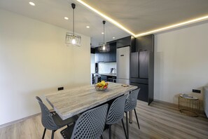 Een moderne keuken met een eethoek, met een houten tafel, metalen stoelen en hanglampen.