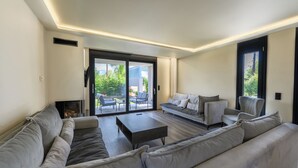 Ein modernes Wohnzimmer mit einer großen Eckcouch, einem Couchtisch und einer Glastür, die zu einer Außenpatiofläche führt.