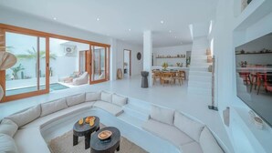 A spacious living area with a large sofa, a dining table, and a kitchen in the background. - "LARRI" - Architect & Luxurious 3BR - Canggu Beach (Bali)