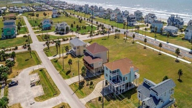 Vista aérea de una zona residencial costera con casas, calles y una playa.