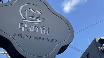 A hotel sign with a logo and contact number.