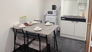 A compact room with a dining table set for two, a microwave, a sink, and a compact kitchenette. - Hoshi No Yado (Osaka)