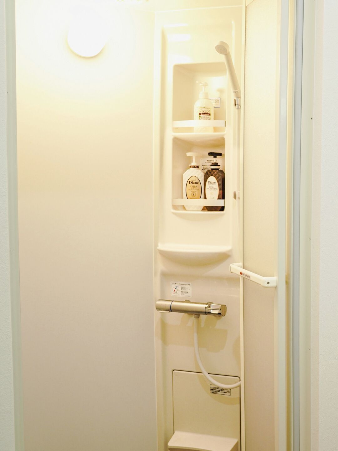 Un baño con un inodoro, un secador de manos y un estante con artículos de aseo.