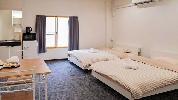A hotel room with two beds, a desk, a chair, a window with curtains, a sink, and a coffee maker. - Hoshi No Yado (Osaka)