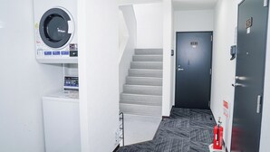 A hotel hallway with a washing machine, a staircase, and a door labeled 201. - Hoshi No Yado (Osaka)