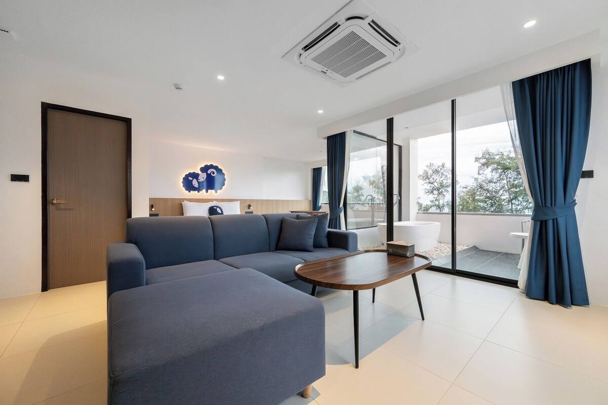A modern living room with a sectional sofa, a round coffee table, and a large window with curtains.