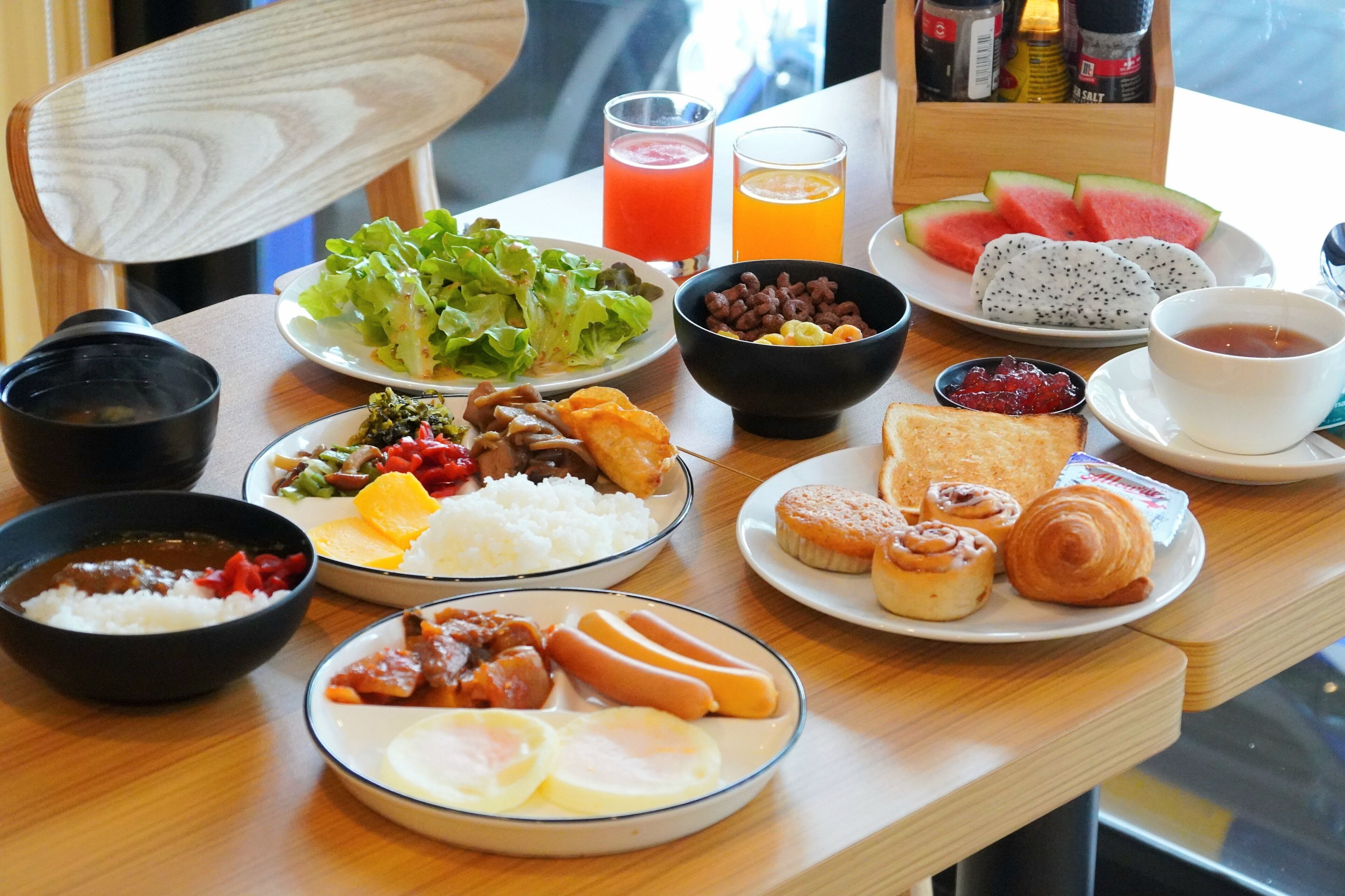 Une table de petit-déjeuner avec divers plats, boissons et condiments.