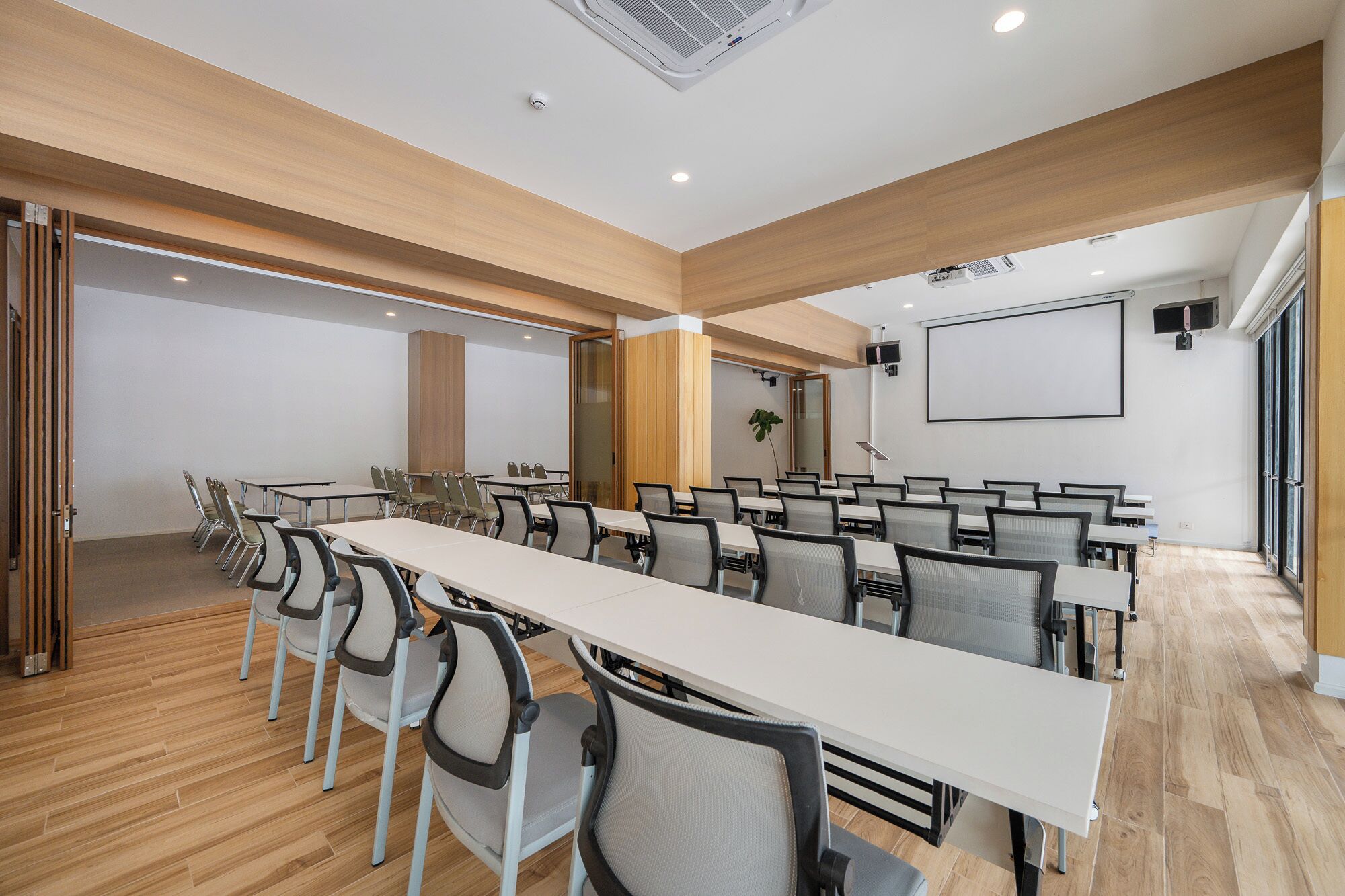 A conference room with a long table, chairs, a projector screen, and a whiteboard.