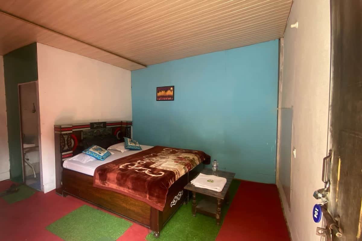 Uma cama de solteiro com cabeceira de madeira, mesa de cabeceira e uma pequena prateleira na parede.