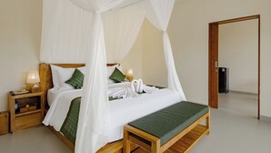 A four-poster canopy bed with white linens, a green throw blanket, and matching pillows. There is a wooden nightstand with a lamp and a small drawer. A bench is placed at the foot of the bed. - Pelana Ubud Villa (Tegallalang)