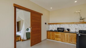 A bedroom with a canopy bed and a separate bathroom visible through an open door. - Pelana Ubud Villa (Tegallalang)