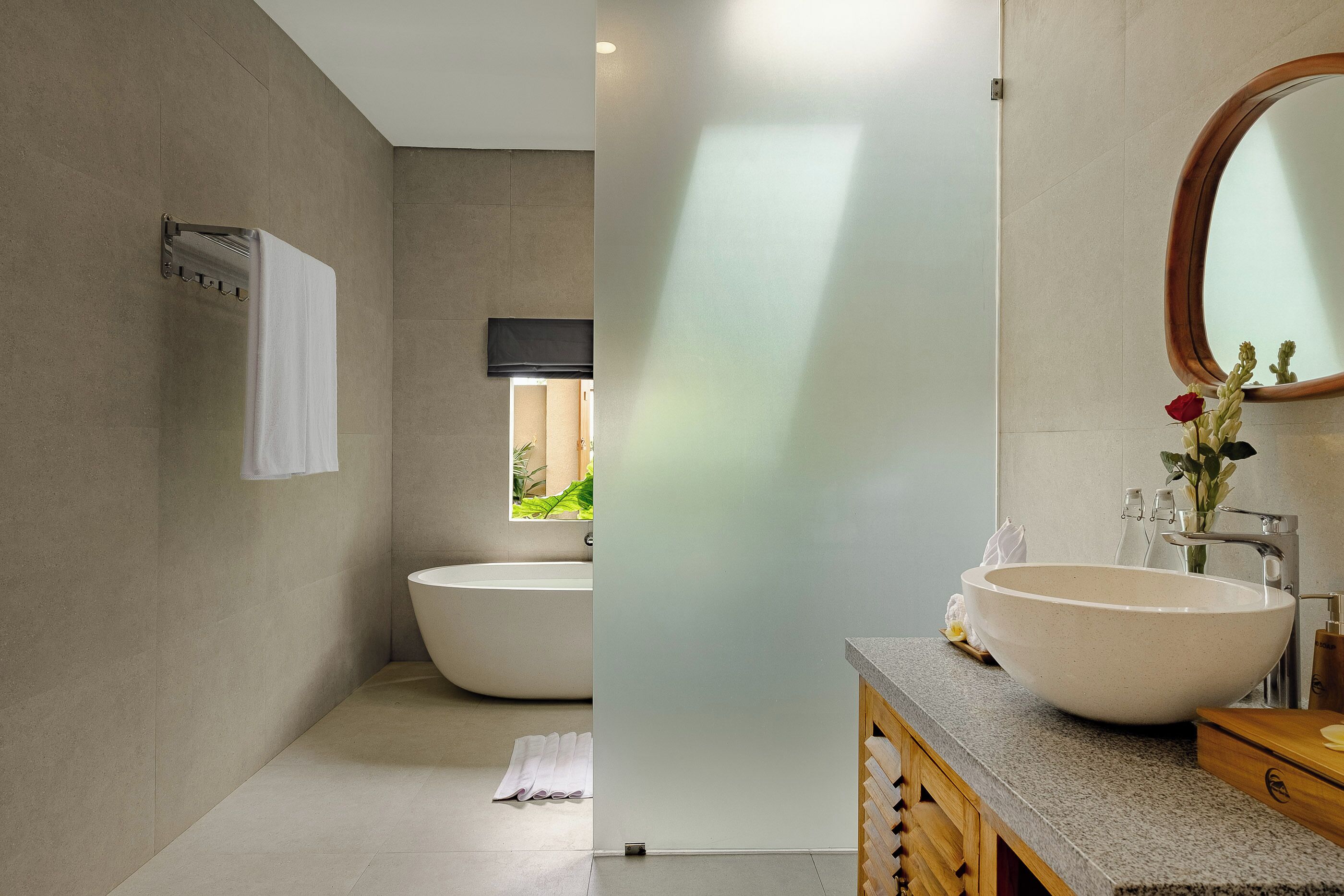 A modern bathroom with a freestanding bathtub, a large vessel sink, and a wooden vanity.