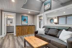 A modern interior with a wooden cabinet, a sofa with cushions, a wooden coffee table, and a poster on the wall.