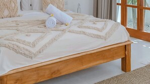 Un dormitorio con cama de madera, lámpara colgante y ventana con cortinas.