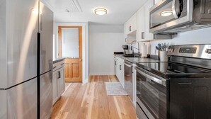 Une cuisine moderne dotée d’appareils électroménagers en acier inoxydable, de planchers en bois et de meubles de cuisine blancs.