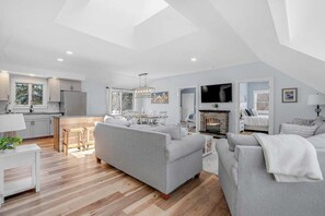 A spacious living area with a sofa, a dining table, and a kitchen in the background.