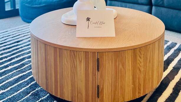 Ein runder Holztisch mit einer weißen Vase und einer Karte in der Mitte.