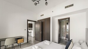 A modern hotel room with a bed, a desk, and a bathroom visible through an open door. - Merano - 805 1BD in Dubai (Dubai)