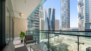 A modern living room with a glass balcony overlooking a cityscape. - Merano - 805 1BD in Dubai (Dubai)