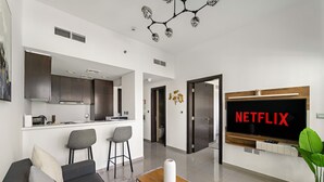 A modern living room with a sofa, a coffee table, and a TV displaying 'NETFLIX'. - Merano - 805 1BD in Dubai (Dubai)