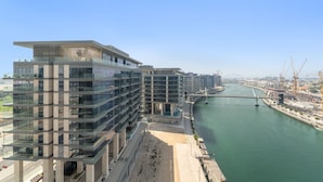 A modern high-rise building with multiple balconies overlooking a river and a bridge. - Canal Front Building 9 A - 1001 2BD (Dubai)