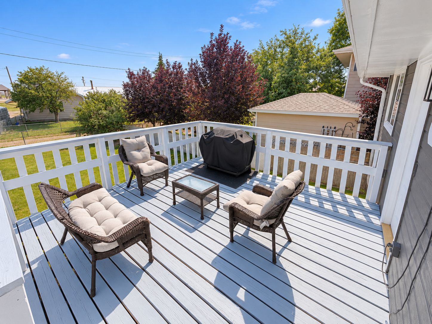 A deck with wicker furniture, a table, and a grill.