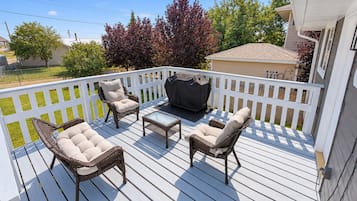 A deck with wicker furniture, a table, and a grill.