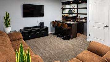 A modern living room with a flat-screen TV, brown sofas, a coffee table, and a potted plant.