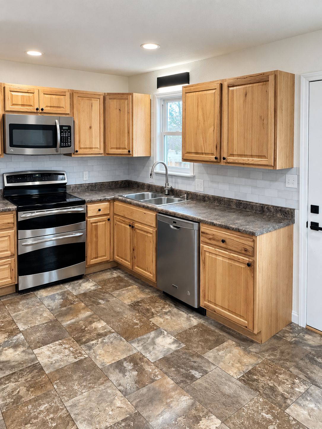 A kitchen with wooden cabinets, stainless steel appliances, a granite countertop, and a tiled floor.