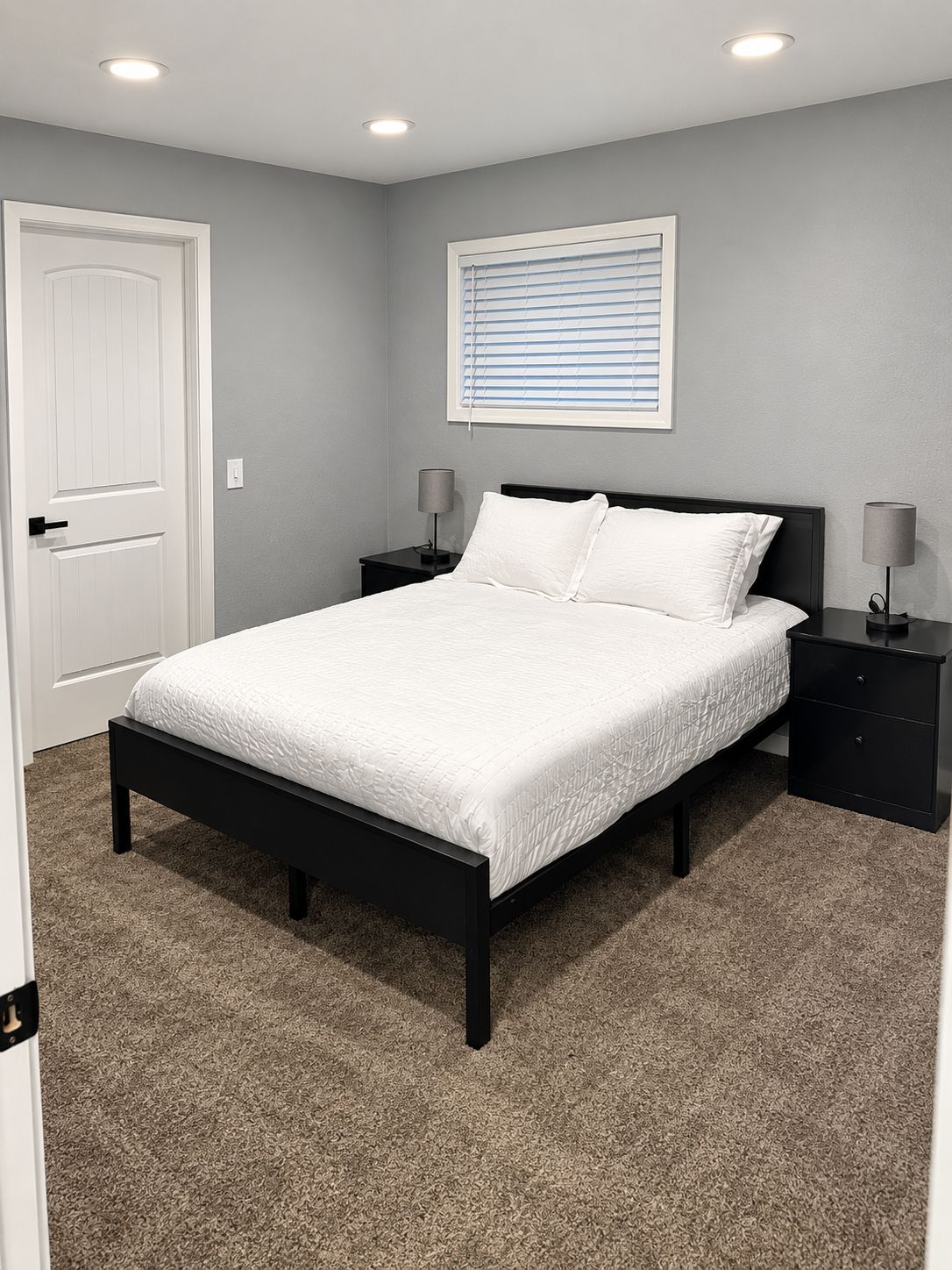 Een slaapkamer met een bed, twee nachtkastjes, een deur en een raam met jaloezieën.