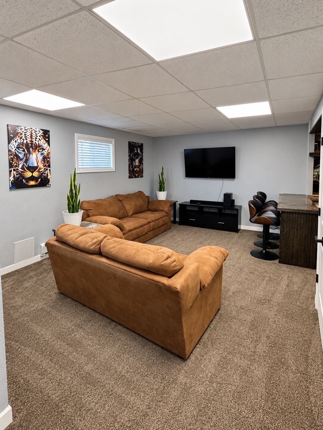 A modern living room with a sectional sofa, a flat-screen TV, and artwork on the walls.