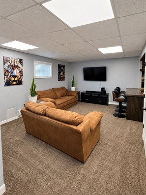 A modern living room with a sectional sofa, a flat-screen TV, and artwork on the walls. - Charming 4-bedroom house. NO ANIMALS. (Wolf Point)