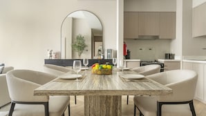 A modern dining area with a wooden table, six chairs, and a fruit basket. - Act Two Tower - 1902 2BD (Dubai)