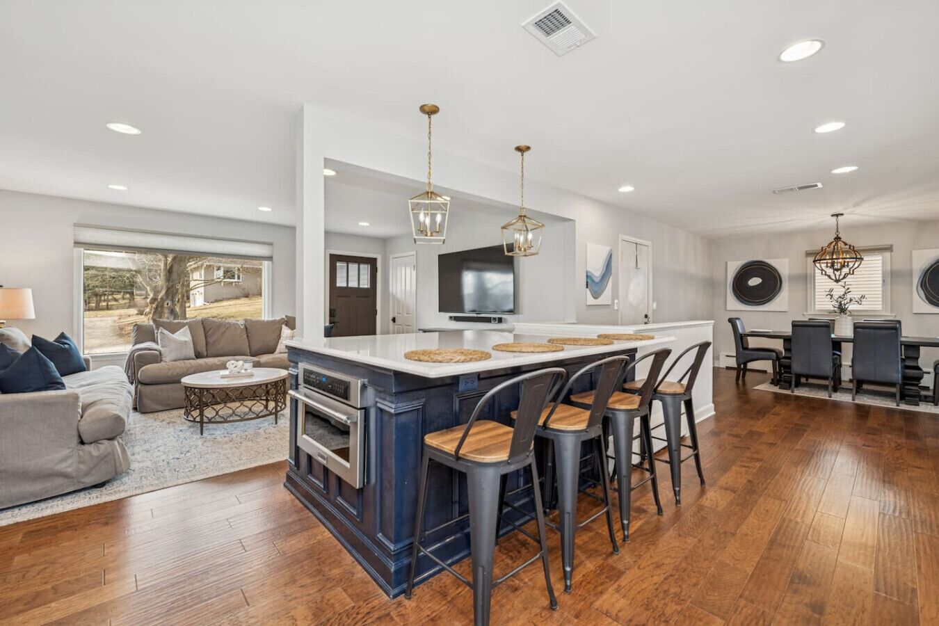 Una cocina moderna con una isla central, taburetes de bar y una zona de comedor con mesa y sillas.