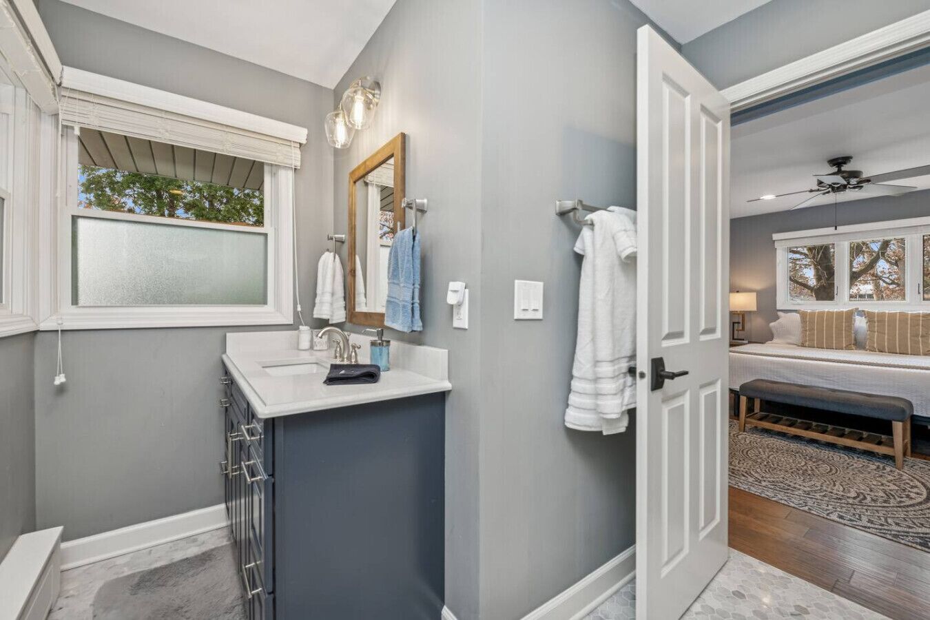 Un baño moderno con tocador, un espejo grande y una ventana.
