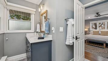 Un baño moderno con tocador, un espejo grande y una ventana.