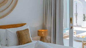 A hotel room with a large bed, a woven wall hanging, a lamp, and a view of the outside.