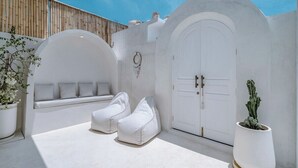 A white exterior with a large arched door, a bench, and two bean bags.