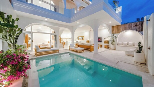A luxurious indoor pool area with multiple seating options and a staircase leading to an upper level.