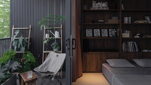 Une chambre moderne avec un lit, une bibliothèque et un espace dédié aux plantes.