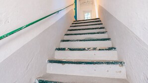 Een trap met witte muren en groen geschilderde treden die naar een deur aan de bovenkant leidt.