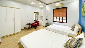 Ein Hotelzimmer mit zwei Betten, einem Schreibtisch, einem Stuhl und einem Fenster mit Jalousien.