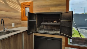 A modern kitchen with a built-in wood finish, a black oven, and a window overlooking a backyard.