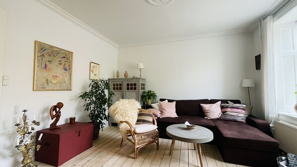 A living room with a dark-colored sofa, a wicker chair, a small round table, and a cabinet with decorative items.