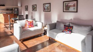 A spacious living room with a high ceiling, tiled floor, and two sofas with colorful cushions. - Los Suspiros Hotel Boutique & Spa (Comala)