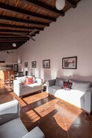 Amplia sala de estar con techo alto, piso de baldosas y dos sofás con cojines de colores.